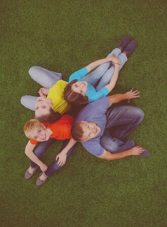 Group of young people sitting on green grassの写真素材