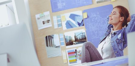 Two young woman standing near desk with instruments, plan and laptop
