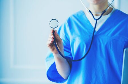 Unknown female doctor with stethoscope standing in medical office.の写真素材