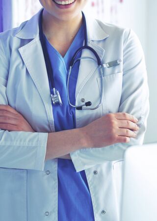 Young woman medic in white uniform standing in clinic's office.の写真素材