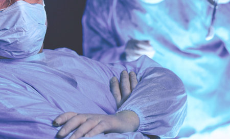 Group of surgeons at work in operating theater toned in blue. Medical team performing operation
