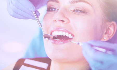 Young Female patient with open mouth examining dental inspection at dentist office.の写真素材