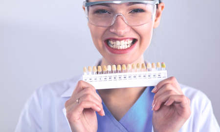 Attractive female dentist with tools , standing on gay backgroundの写真素材