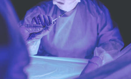 Doctor performing surgery in a dark background.の写真素材