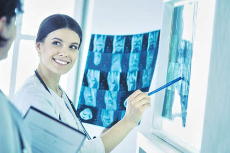Two smiling doctors pointing at x-rays in a hospital consulting roomの写真素材