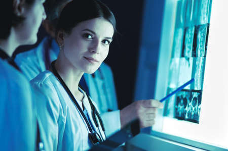 Group of doctors examining x-rays in a clinic, thinking of a diagnosisの写真素材