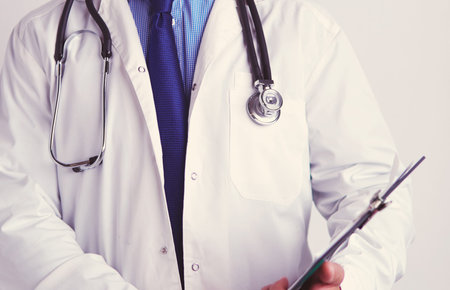 Male doctor standing with folder, isolated on white backgroundの写真素材