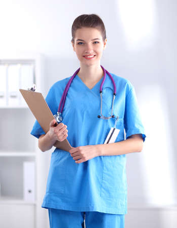 Smiling female doctor with a folder in uniform standing at hospitalの写真素材