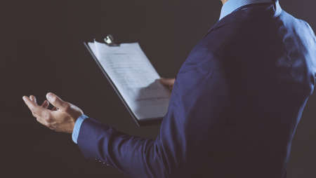 Portrait of successful cheerful cute young man presenting new product, showing copy spase on her palm on grey backgroundの写真素材