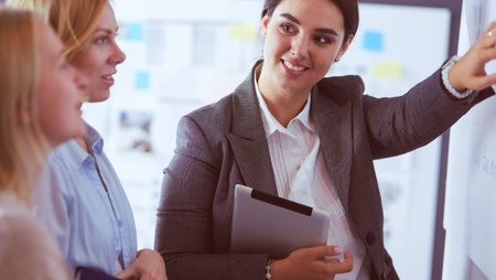 Business, education and office concept - business team with flip board in office discussing...