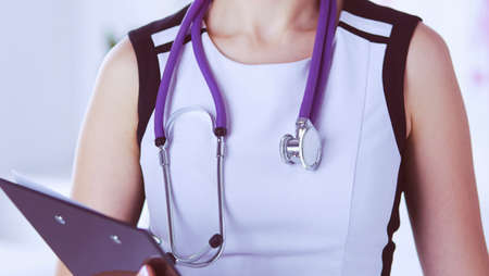Portrait of friendly female doctor with stethoscope and tablet in hands.の写真素材