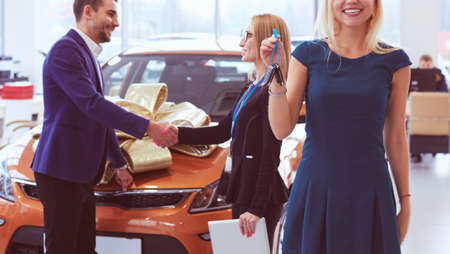 A man makes a gift - a car to his wife. She is surprised at this. They are very happy aboutの写真素材
