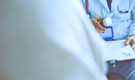 Portrait of doctor explaining bottle of medicine to her patientの写真素材