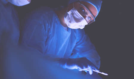 Doctors team in surgery in a dark background.の写真素材