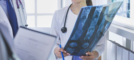 Smiling doctors discussing patients diagnosis looking at x-rays in a hospital