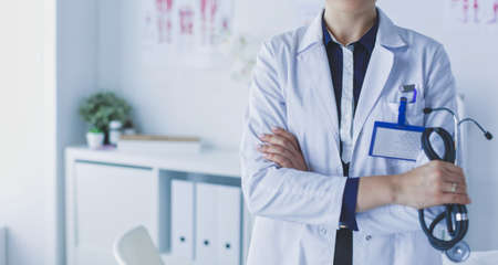 Smiling female doctor with a folder in uniform standingの写真素材