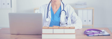 Beautiful young smiling female doctor sitting at the desk and writing. female doctorの写真素材