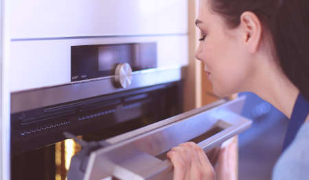 Beautiful young woman checking how her cake is doing in the ovenの写真素材