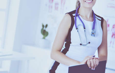 Portrait of friendly female doctor with stethoscope and tablet in hands.の写真素材
