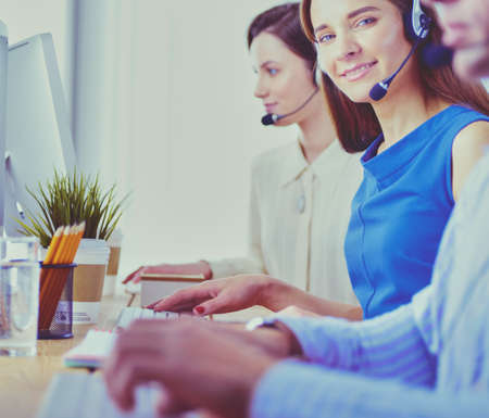 Smiling call center employees sitting in line with their headsetの写真素材