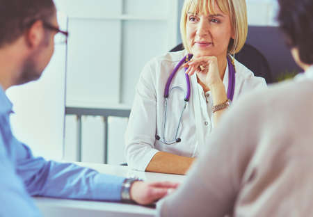Attentive senior doctor listenint to patient in her officeの写真素材