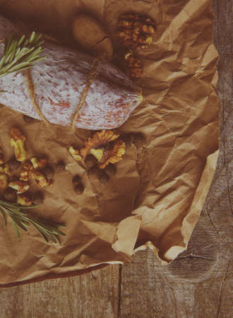 Italian salami wih sea salt, rosemary, garlic and nuts on paper. Rustic style. Top view.の写真素材