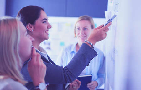 Business, education and office concept - business team with flip board in office discussing something.の写真素材