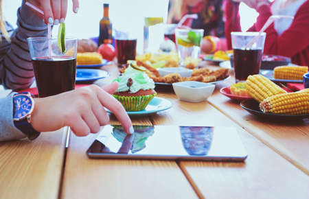 Top view of group of people having dinner together while sitting at wooden table. Food on the table. People eat fast food.の写真素材