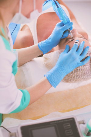 Permanent makeup for eyebrows. Closeup of beautiful woman with thick brows in beauty salon.