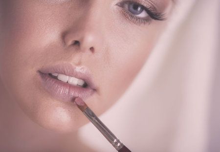 A picture of a young woman applying face powder in the bathroomの写真素材