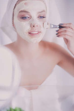 A picture of a young woman applying face powder in the bathroomの写真素材