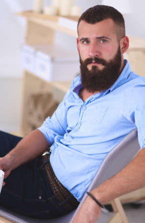 Young man sitting with laptop and a tea cup at homeの写真素材