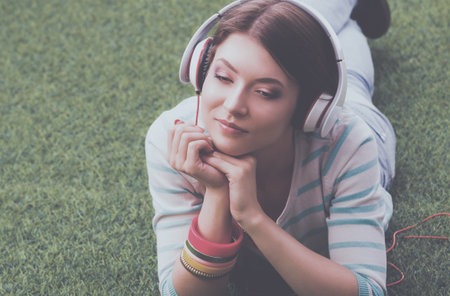 Woman listening to the music lying on green grassの写真素材
