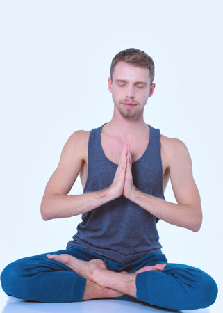 Adult man doing yoga exercise on white backgroundの写真素材