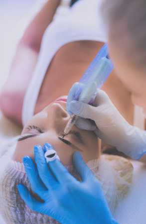 Permanent makeup for eyebrows. Closeup of beautiful woman with thick brows in beauty salonの写真素材