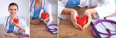 Young doctor with red heart symbol sitting at deskの写真素材