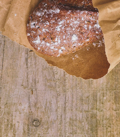 A loaf of Bread packed in paper on wooden table