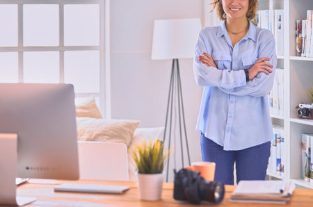 Portrait of smiling young woman with dslr photo camera standing in loft apartmentの写真素材