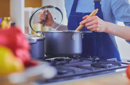 Cooking woman in kitchen with wooden spoonの写真素材