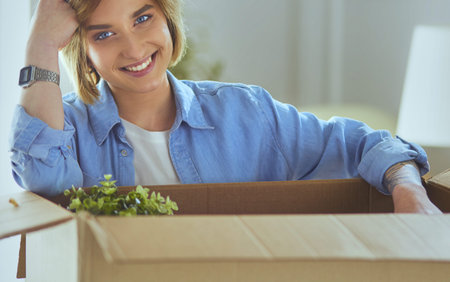 A beautiful single young woman unpacking boxes and moving into a new home
