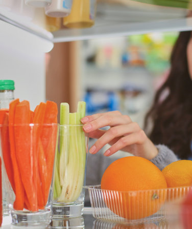 Portrait of female standing near open fridge full of healthy food, vegetables and fruits. Portrait of femaleの写真素材