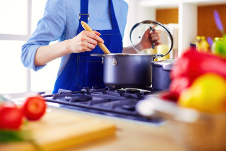 Cooking woman in kitchen with wooden spoonの写真素材
