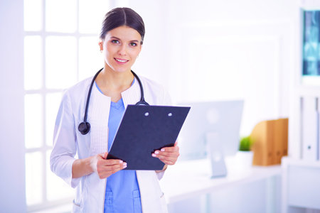 Young smiling female doctor with stethoscope holding a folder at doctors officeの写真素材