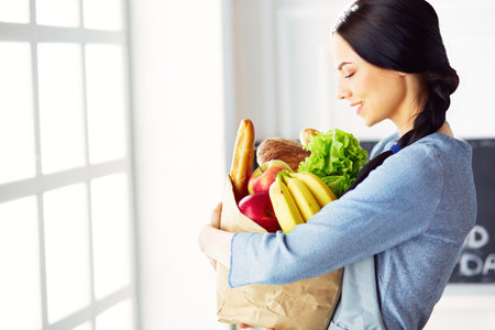 Young woman holding grocery shopping bag with vegetablesの写真素材