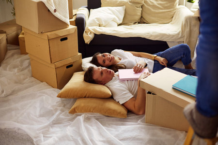 High view of happy couple lying on floor with a lot of boxesの写真素材