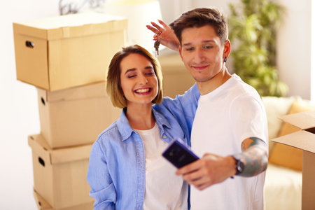 Young couple taking selfies with her smartphone in their new homeの写真素材