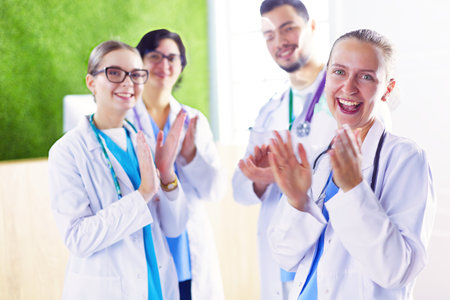 Happy medical team comprising male and female doctors smiling broadly and giving a thumbs up of success and hopeの写真素材
