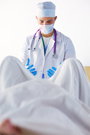 male obstetrician and scrubs nurse are delivered to the pregnant woman in the delivery room of the hospitalの写真素材