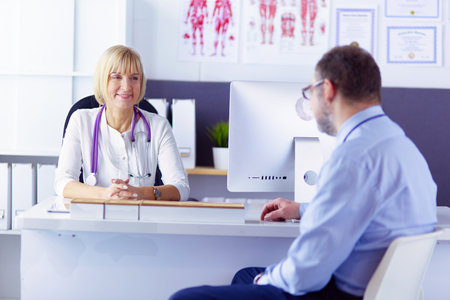 doctor talking to her male patient at officeの写真素材