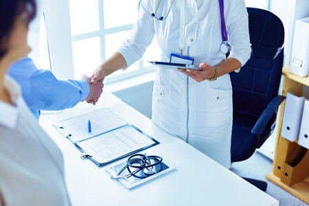 Woman doctor handshaking with a senior coupleの写真素材
